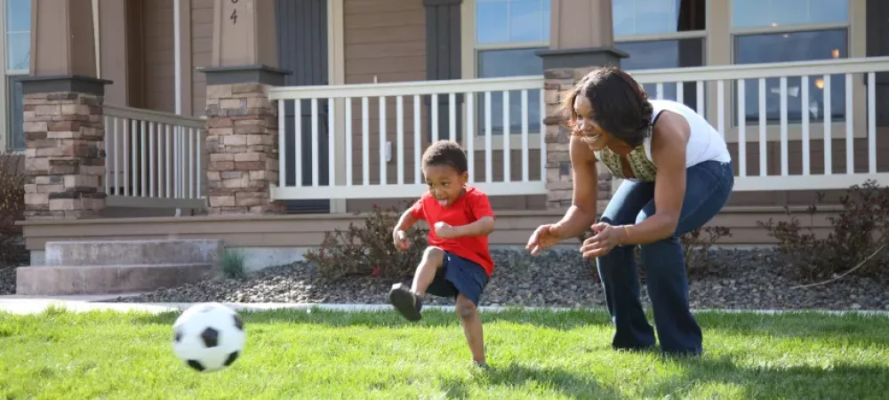 Boy and Mom playing soccer in grass